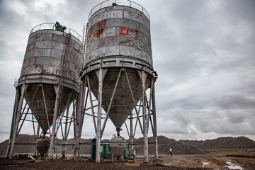 Asphalt mixing plant after the rain on cloudy grey sky background.