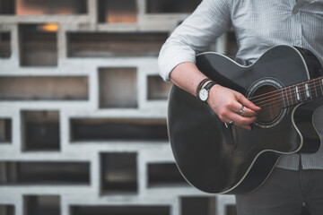 Anonymous man is playing a guitar at outside with trendy colors, headless photo with copy space.