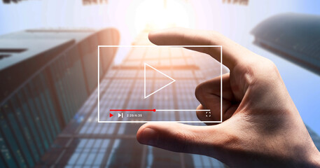 Hand holdig play button over business building