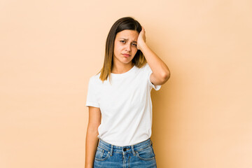 Young woman isolated on beige background tired and very sleepy keeping hand on head.