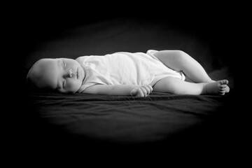 Obraz premium Newborn baby sleeps on a black background.