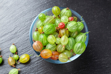 Ripe gooseberry in a glass plate, place for text, top view