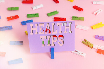 Handwriting text writing Health Tips. Conceptual photo advice or information given to be helpful in being healthy Colored clothespin papers empty reminder pink floor background office pin