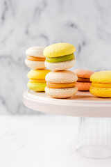 Colorful french macarons on a pink plate on marble background