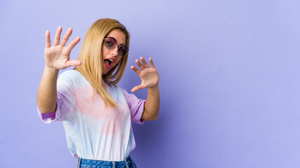 Young hipie woman with glasses isolated on purple background being shocked due to an imminent danger