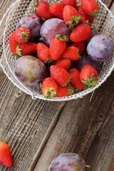 Ripe plums and strawberries on a wooden table