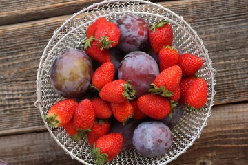 Ripe plums and strawberries on a wooden table