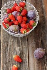 Ripe plums and strawberries on a wooden table