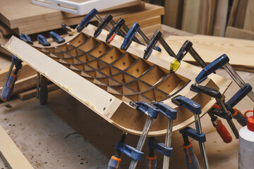 Joinery. Plywood bending process. Gluing and clamping bend wooden panel. Bend furniture manufacture