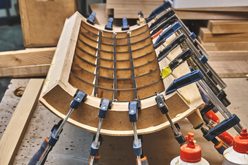 Joinery. Plywood bending process. Gluing and clamping bend wooden panel. Bend furniture manufacture