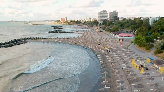 Aerial view of an empty  beach situated in Constanta city Romania  Jupiter beach in sunrise light.
view of reeds beach umbrellas.
Drone descending