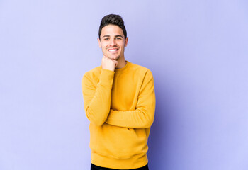 Young caucasian man isolated on purple background smiling happy and confident, touching chin with hand.