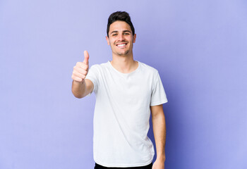 Young caucasian man isolated on purple background smiling and raising thumb up
