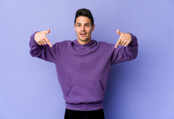 Fototapeta premium Young caucasian man isolated on purple background points down with fingers, positive feeling.