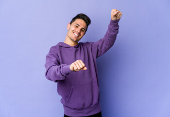 Young caucasian man isolated on purple background dancing and having fun.