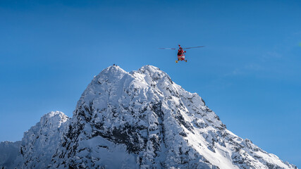 Naklejka na ściany i meble Rescue helicopter saved mountain climbers. People on the top of Swinica steep and rocky mountain peak at winter, Tatra Mountains, Poland