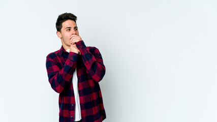 Young caucasian man isolated on white background thoughtful looking to a copy space covering mouth with hand.