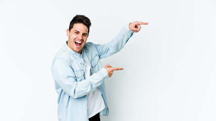 Young caucasian man isolated on white background pointing with forefingers to a copy space, expressing excitement and desire.