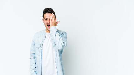 Young caucasian man isolated on white background having fun covering half of face with palm.