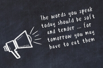 Chalk loudspeaker and wise quote on black desk