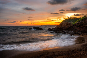 Amazing beach sunset with endless horizon and lonely figures in the distance, and incredible foamy waves.Rayong Beach, Thailand