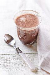 Glass of chocolate milkshake on bright wooden background. Close up. 