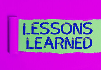 Fototapeta premium Conceptual hand writing showing Lessons Learned. Concept meaning the knowledge or understanding gained by experience Rolled ripped torn cardboard above a wooden classic table