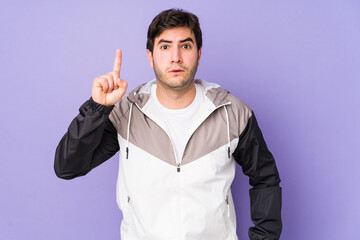Fototapeta premium Young man isolated on purple background pointing upside with opened mouth.