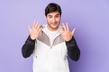 Young man isolated on purple background showing number ten with hands.