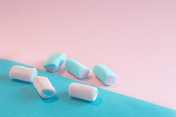 Photo in pastel colors. Three pink and three blue marshmallows lie on a pink and pale blue background. Soft focus, selective focus. Idea - background, advertisement, treats, sweets.