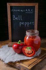 In the photo, bell pepper sliced in a jar, pepper lying on a stand for vegetables with a board with inscriptions.