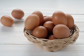 Fresh chicken eggs in the basket on white wooden background
