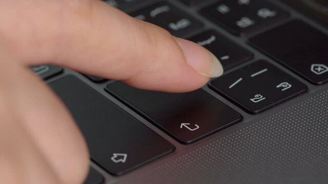 close-up female hand pressing enter button on a laptop keyboard
