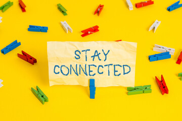Writing note showing Stay Connected. Business concept for to remain having social professional commercial relationship Colored clothespin papers empty reminder yellow floor background office