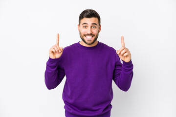 Young caucasian man against a white background isolated indicates with both fore fingers up showing...