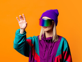 Style woman in 90s tracksuit with VR glasses on orange background