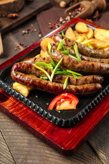 Grilled sausages with potatoes on the wooden table