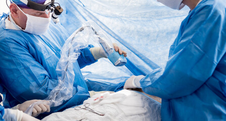The surgeon uses a portable fluorescence imaging device during breast removal.