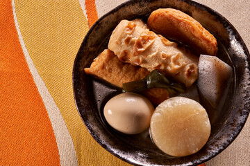 黒い皿に盛りつけられたおでん（煮物）