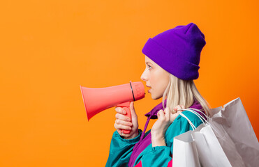 Style woman in 90s tracksuit with megaphone and shopping bags