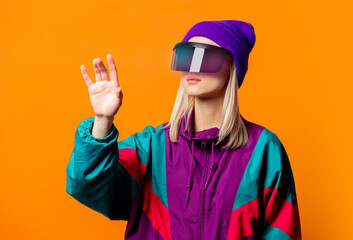 Style woman in 90s tracksuit with VR glasses on orange background