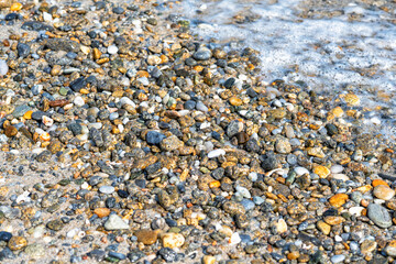 Pebbles beach and water as background. Different forms minerals as natural texture multicolor backdrop