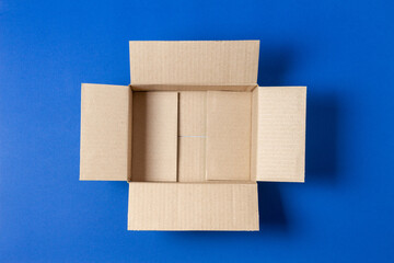 One empty open brown cardboard box on blue background. Top view