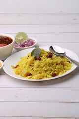 Aloo/Kanda Poha or Tarri Pohe with spicy chana masala/curry. Served in ceramic plate.