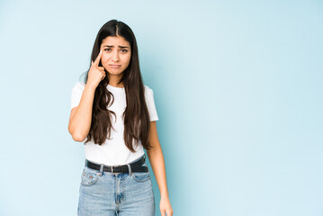 Fototapeta premium Young indian woman on blue background crying, unhappy with something, agony and confusion concept.