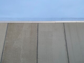 Prison wall with barbed wire and blue sky