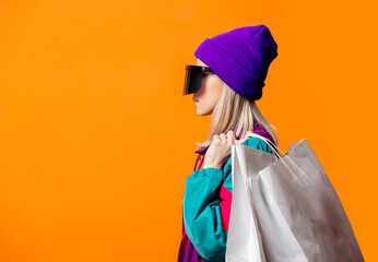 Style woman in 90s tracksuit and VR glasses with shopping bags