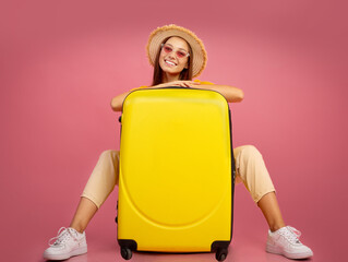 Pretty lady in summer hat and sunglasses posing with suitcase
