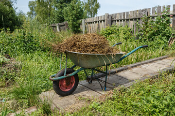 garden cart with natural cow dung. The cart is on a wooden bridge near the fence.