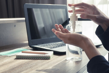 Fototapeta premium Women hands pumping antibacterial hand sanitizer gel for killing disease while working from home in quarantine for Covid-19 outbreak. Work from home concept. Pandemic protection concept